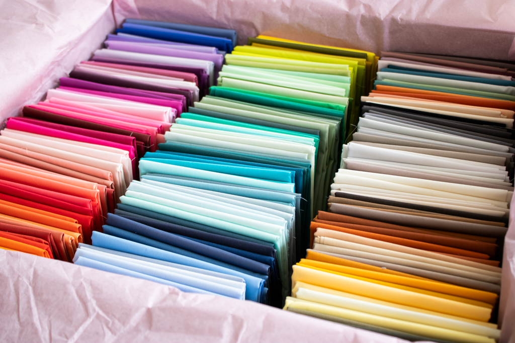 Assorted fat quarter fabric bundle with folded pastel and bold colors in trays