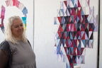 Quilt retreat participant in gray top, standing beside red white blue quilt block display