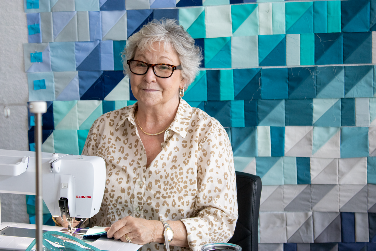Quilt retreat participant sewing at Bernina machine, wearing leopard-print blouse