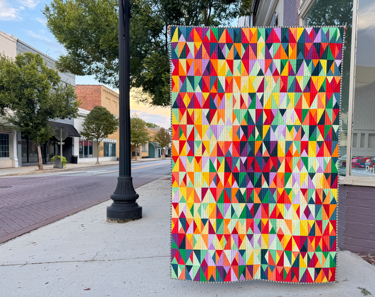 Multicolor geometric triangle quilt hanging outdoors, full patchwork panel