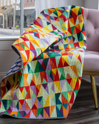 Multicolor geometric triangle quilt over chair, colorful patchwork with border