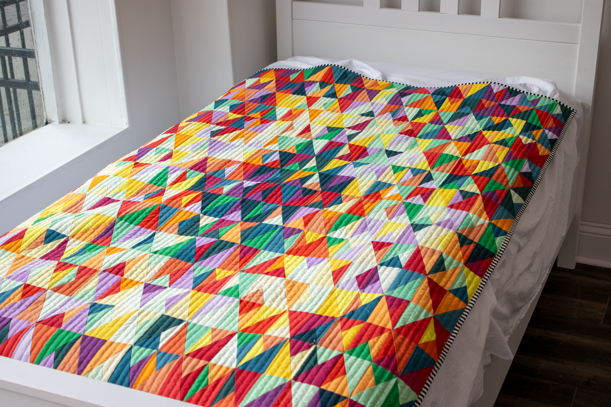 Multicolor geometric triangle quilt on bed with bright patchwork top